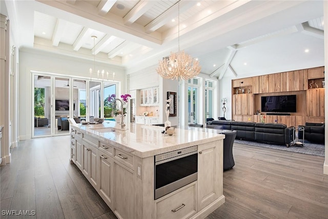 kitchen with sink, beamed ceiling, an island with sink, pendant lighting, and hardwood / wood-style flooring