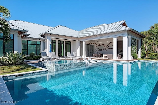 rear view of property with ceiling fan and a swimming pool with hot tub