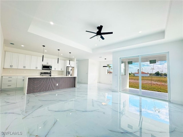 unfurnished living room featuring a raised ceiling and ceiling fan