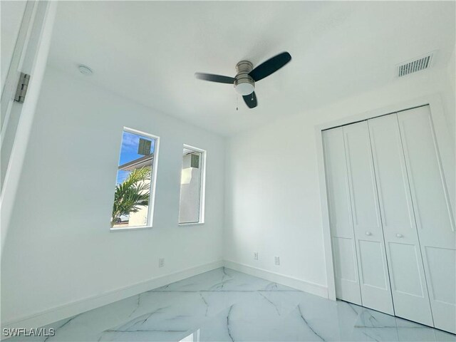 unfurnished bedroom featuring ceiling fan and a closet