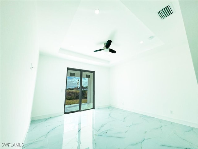 unfurnished room featuring a raised ceiling and ceiling fan