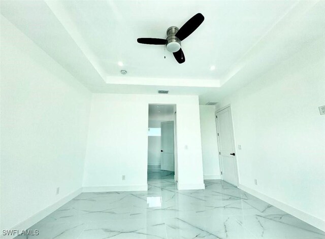 unfurnished bedroom featuring ceiling fan and a raised ceiling