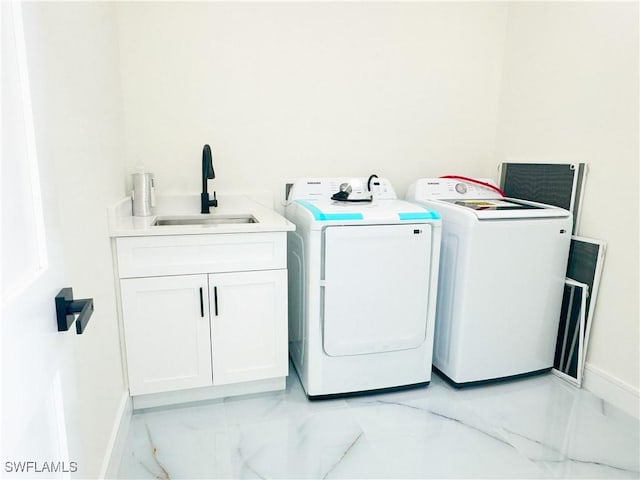 clothes washing area with washing machine and dryer, sink, and cabinets