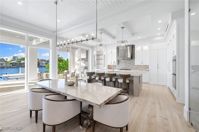 dining area with wooden ceiling, a water view, a healthy amount of sunlight, and light wood-type flooring