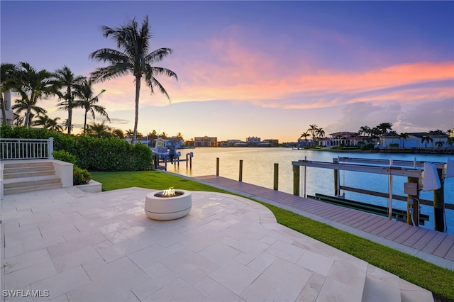 dock area with a water view, a fire pit, and a patio area