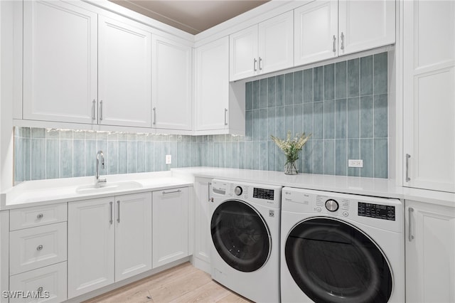 laundry room featuring separate washer and dryer, sink, cabinets, and light wood-type flooring