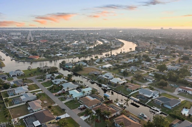 aerial view at dusk featuring a water view