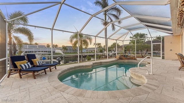 pool at dusk featuring a lanai, a water view, and a patio