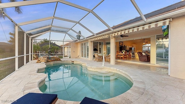 view of swimming pool featuring glass enclosure, ceiling fan, and a patio