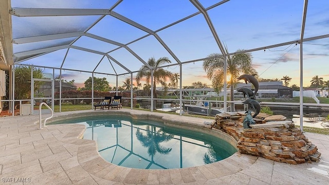 pool at dusk featuring a lanai and a patio