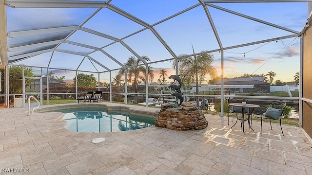 pool at dusk featuring a lanai and a patio area