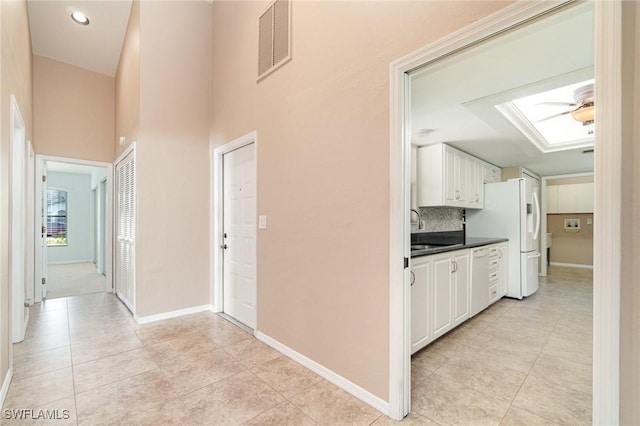 corridor featuring sink and light tile patterned flooring