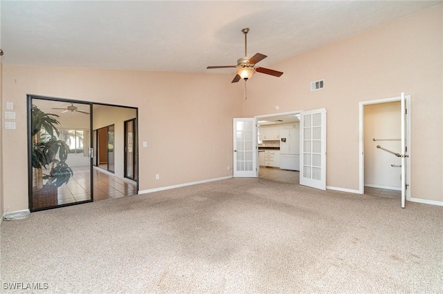 unfurnished living room with ceiling fan, vaulted ceiling, light colored carpet, and french doors