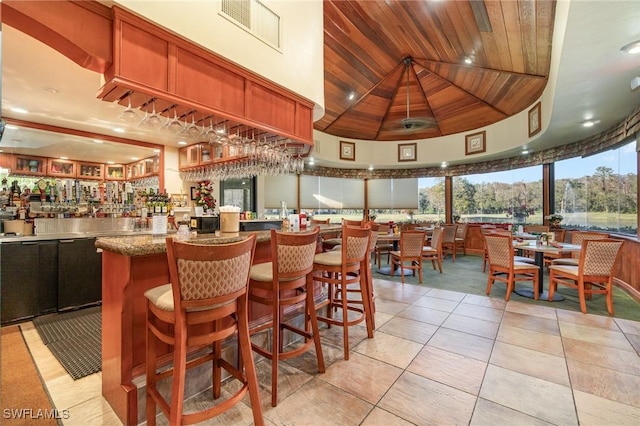 bar featuring light tile patterned flooring, wooden ceiling, and high vaulted ceiling