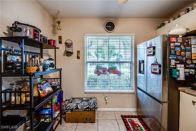 kitchen with stainless steel fridge, white cabinets, a healthy amount of sunlight, and light tile patterned floors