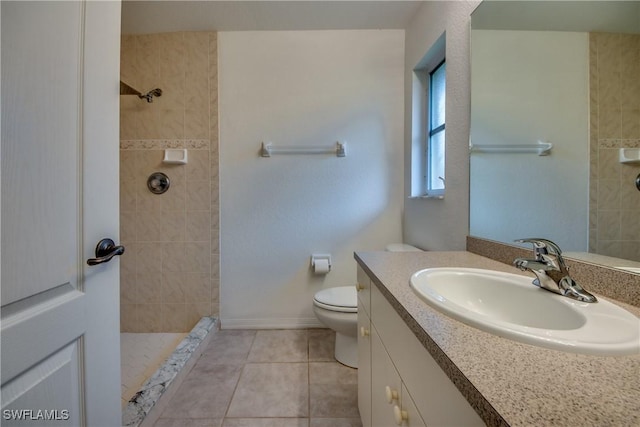 bathroom featuring tile patterned flooring, vanity, toilet, and a tile shower