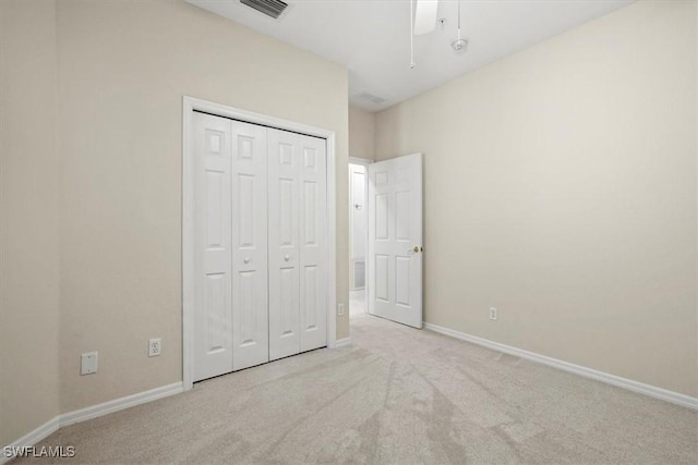 unfurnished bedroom with ceiling fan, a closet, and light carpet