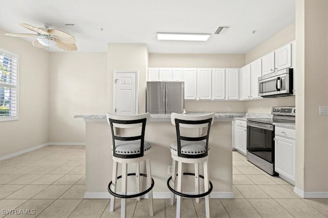 kitchen with white cabinetry, a breakfast bar, a center island, and appliances with stainless steel finishes