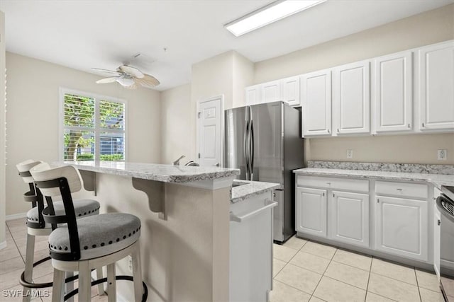 kitchen with a center island, a breakfast bar, white cabinets, and ceiling fan