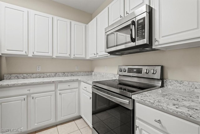 kitchen featuring white cabinetry, light stone counters, stainless steel appliances, and light tile patterned flooring