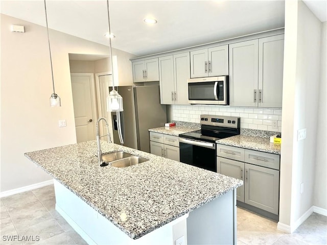 kitchen with pendant lighting, a kitchen island with sink, sink, and appliances with stainless steel finishes