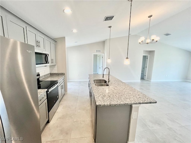 kitchen featuring stainless steel appliances, sink, decorative light fixtures, a center island with sink, and lofted ceiling