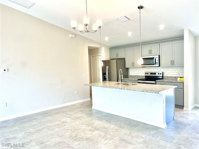 kitchen with a center island with sink, decorative light fixtures, light stone countertops, appliances with stainless steel finishes, and a notable chandelier