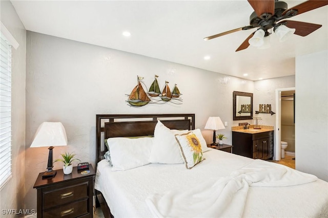 bedroom with ceiling fan, sink, ensuite bathroom, and multiple windows