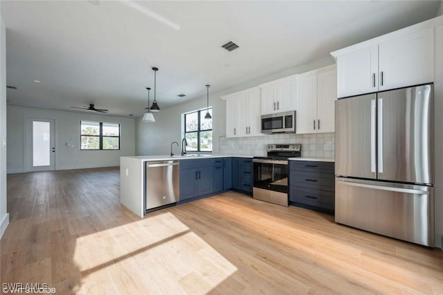 kitchen featuring pendant lighting, kitchen peninsula, white cabinetry, appliances with stainless steel finishes, and blue cabinetry