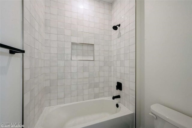 bathroom featuring toilet and tiled shower / bath