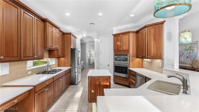 kitchen with sink, stainless steel appliances, light tile patterned floors, decorative backsplash, and a kitchen island