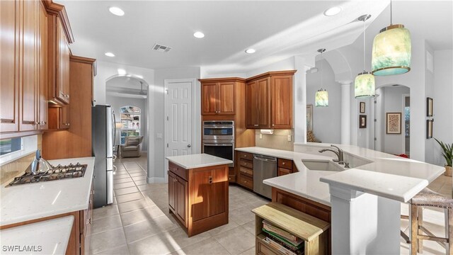 kitchen featuring sink, pendant lighting, a kitchen island with sink, a breakfast bar, and appliances with stainless steel finishes