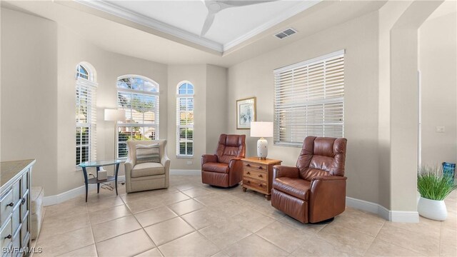 living area with light tile patterned floors, a raised ceiling, ceiling fan, and ornamental molding