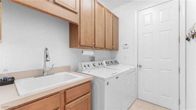 clothes washing area featuring washer and clothes dryer, light tile patterned flooring, cabinets, and sink