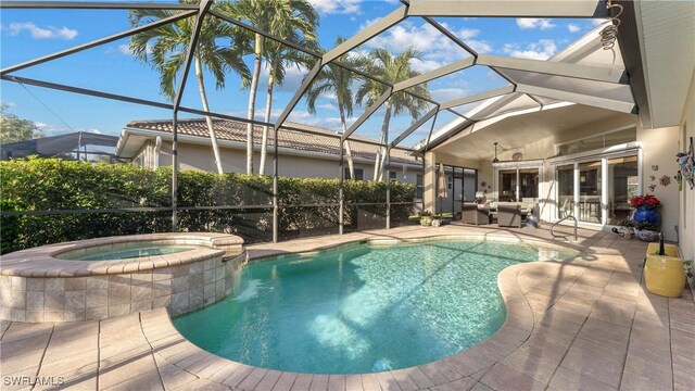 view of swimming pool with glass enclosure, a patio area, and an in ground hot tub