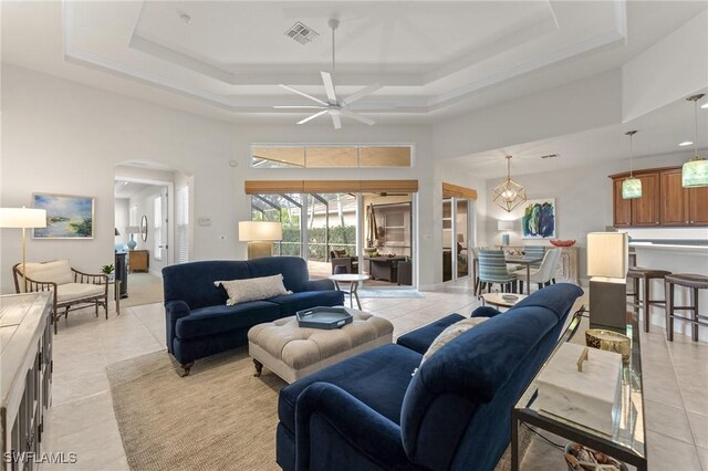 tiled living room featuring a raised ceiling, ceiling fan, and a towering ceiling