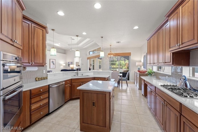 kitchen with kitchen peninsula, stainless steel appliances, a kitchen island, and hanging light fixtures