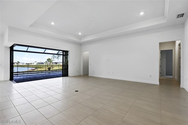 tiled empty room with a water view and a tray ceiling