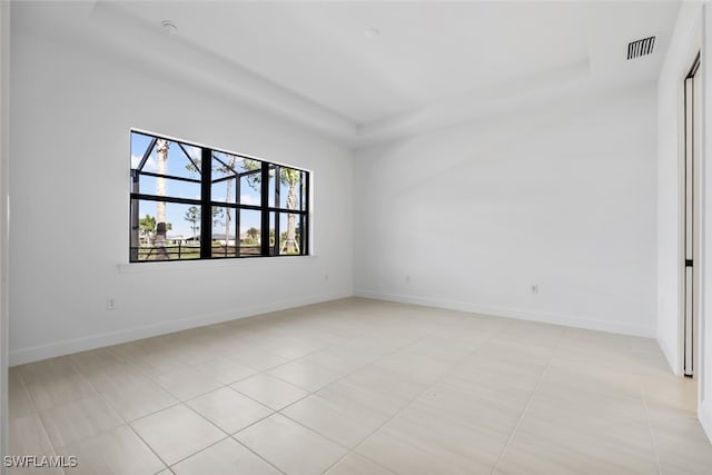 tiled spare room featuring a raised ceiling