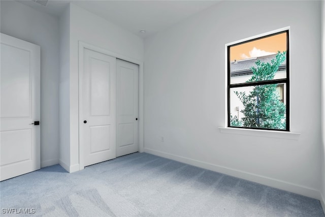 unfurnished bedroom featuring multiple windows, a closet, and light colored carpet