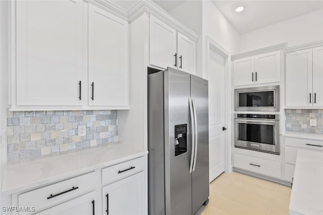 kitchen with white cabinets, stainless steel appliances, light stone counters, and tasteful backsplash