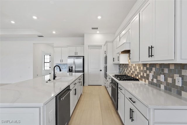 kitchen featuring custom exhaust hood, stainless steel appliances, sink, a large island with sink, and white cabinets