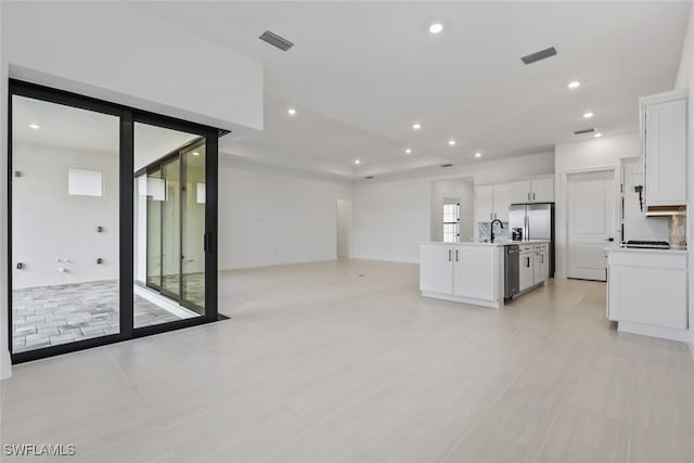 kitchen featuring sink, light tile patterned floors, an island with sink, appliances with stainless steel finishes, and white cabinetry