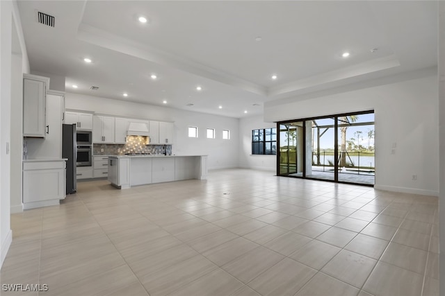 unfurnished living room with a raised ceiling and light tile patterned floors