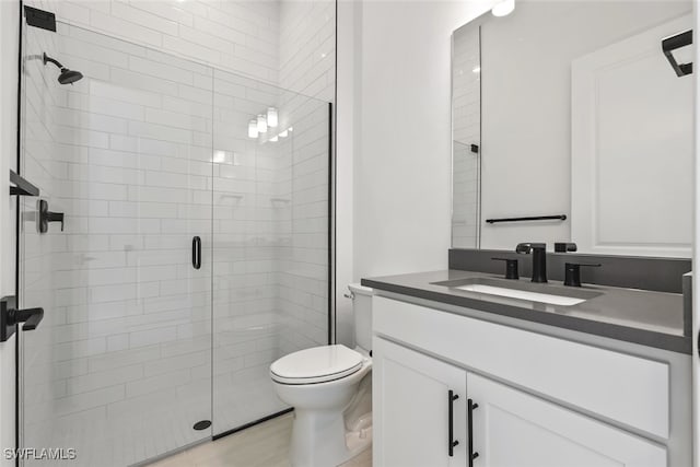 bathroom featuring vanity, an enclosed shower, and toilet