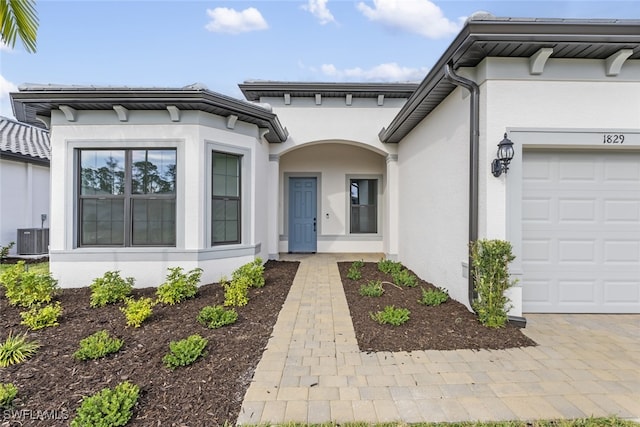 view of exterior entry featuring a garage and central air condition unit