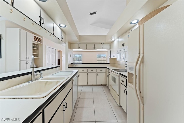 kitchen with light tile patterned floors, white appliances, white cabinetry, and sink