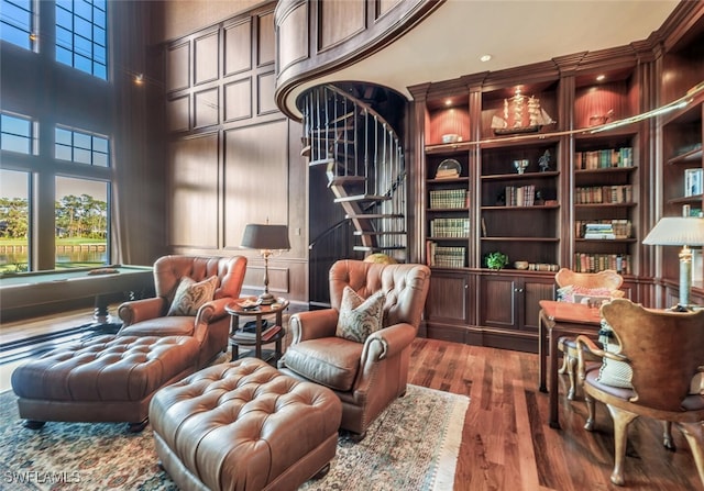 sitting room featuring hardwood / wood-style flooring, built in shelves, a towering ceiling, and billiards