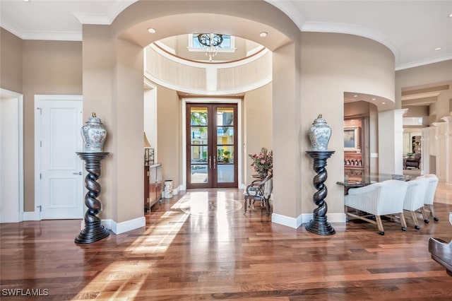 foyer entrance with a chandelier, wood-type flooring, a towering ceiling, and french doors