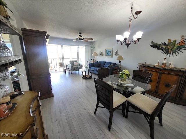 dining space featuring a textured ceiling, ceiling fan with notable chandelier, and light wood-type flooring